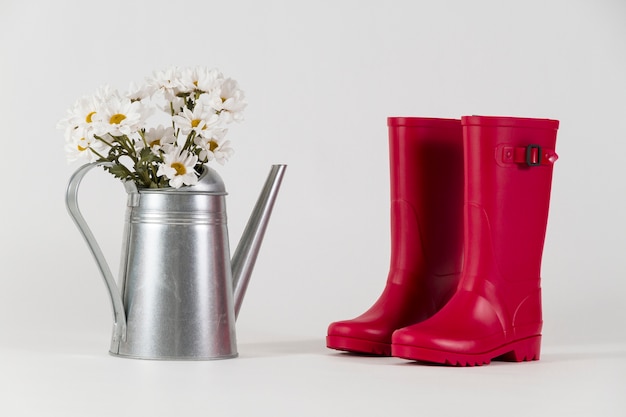 Wasser Stiefel neben einer Gießkanne mit Blumen