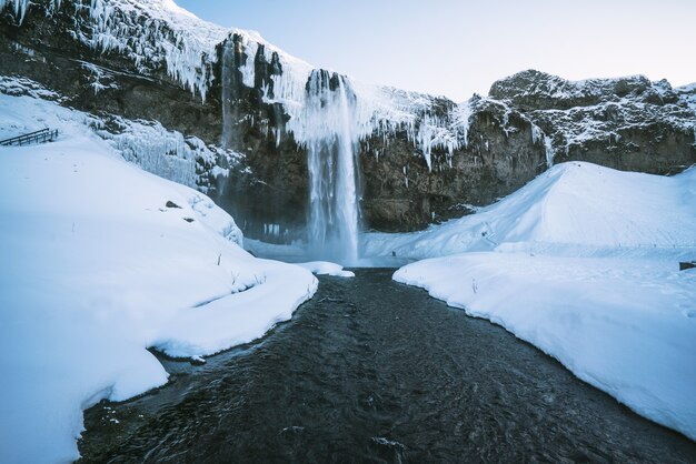 Wasserfälle fließen zwischen Schnee