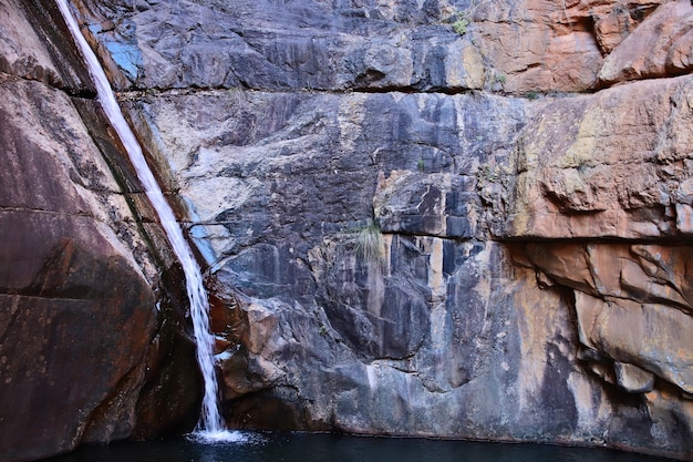 Wasserfall fließt durch eine Felsformation und strömt in den Fluss