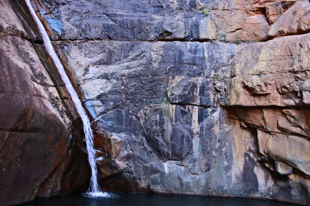 Wasserfall fließt durch eine Felsformation und strömt in den Fluss