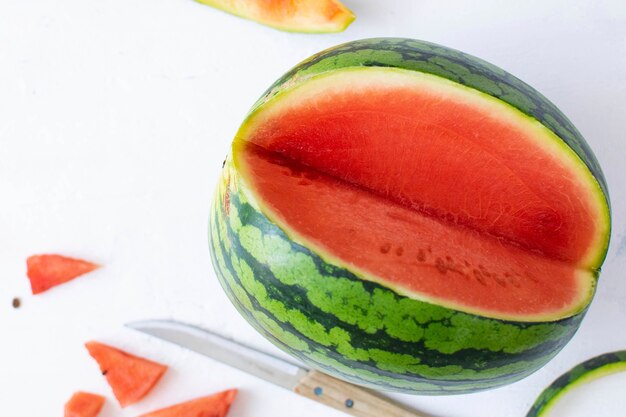 Wassermelone mit Messer auf weißem Tisch