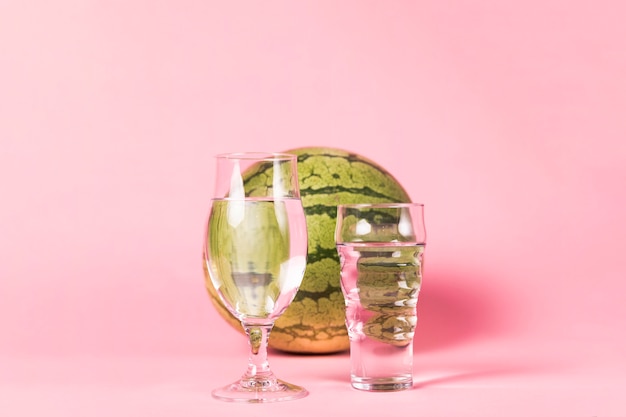 Wassermelone und Gläser auf rosa Hintergrund