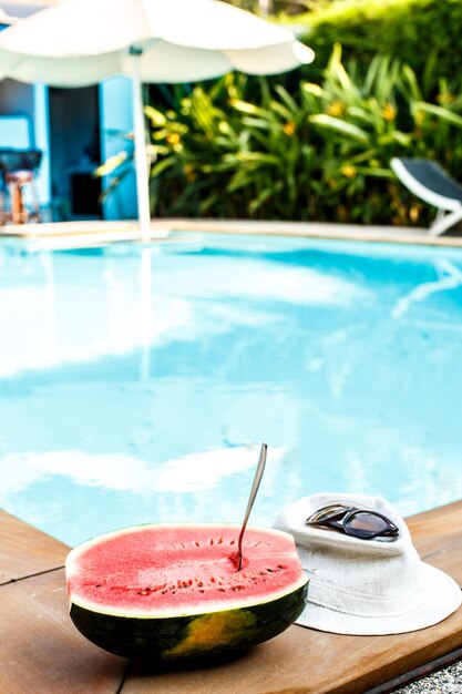 Wassermelone und Gläser in der Nähe des Pools