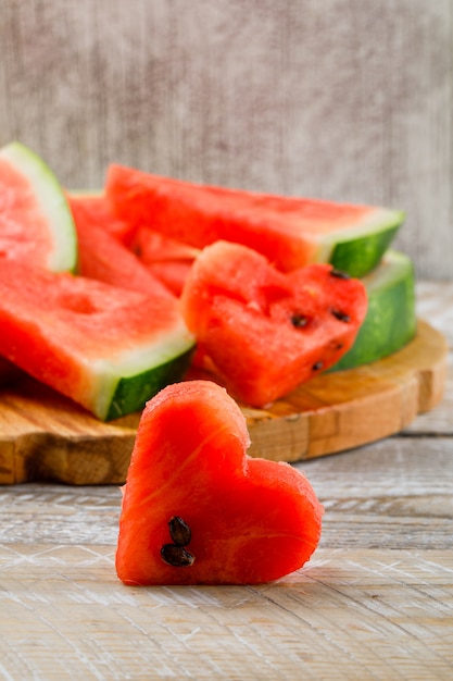 Wassermelonenscheiben auf einer Seitenansicht des Schneidebretts auf Holz- und Schmutzhintergrund