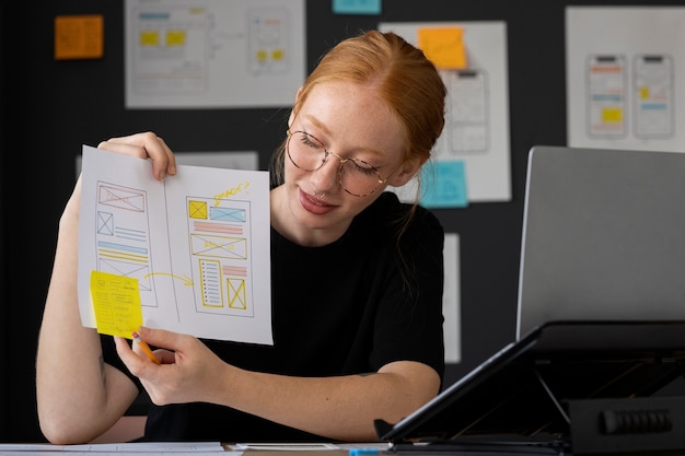 Webdesignerin mit Papieren und Notizen im Büro