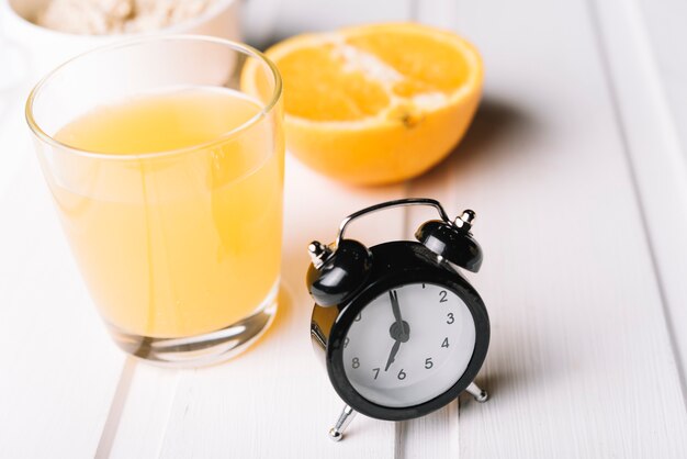 Wecker mit frischem Glas eines Orangensaftes über der Tabelle