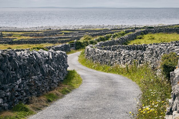 Weg in Inisheer umgeben von Felsen und dem Meer unter dem Sonnenlicht in Irland