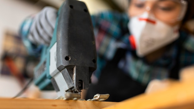 Weibliche Arbeit in der Werkstatt mit Bohrhammer hautnah