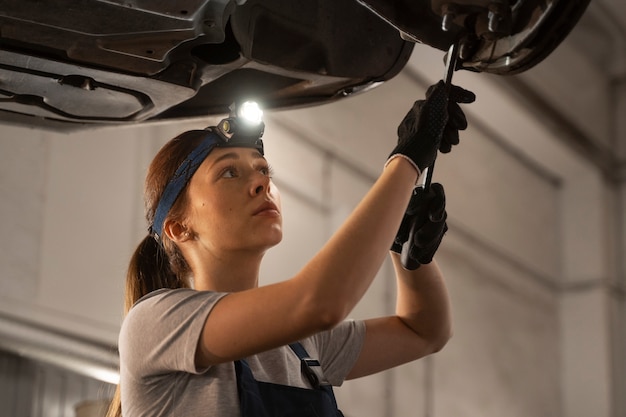 Kostenloses Foto weibliche autowerkstatt, die in der werkstatt an einem auto arbeitet