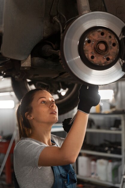 Weibliche Autowerkstatt, die in der Werkstatt an einem Auto arbeitet