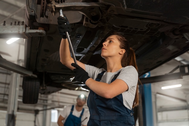 Kostenloses Foto weibliche autowerkstatt, die in der werkstatt an einem auto arbeitet