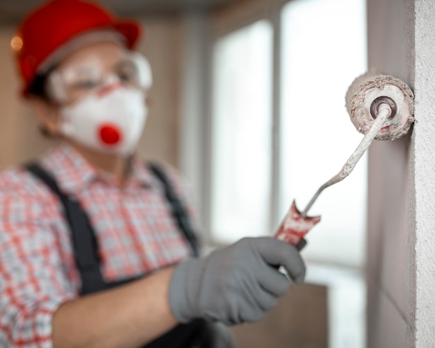 Kostenloses Foto weibliche bauarbeiterin mit helm und farbroller