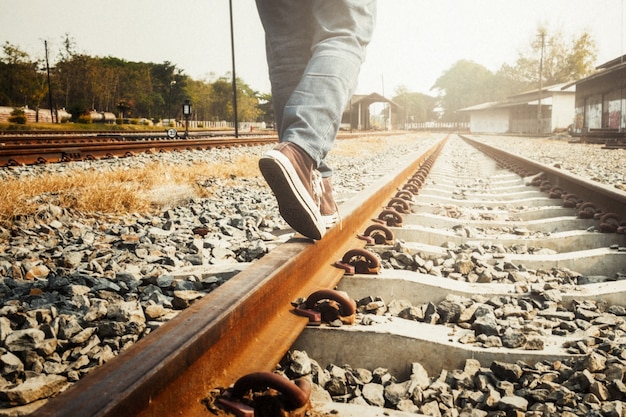 Weibliche Beine in Sneakers auf der Schiene der Eisenbahn.