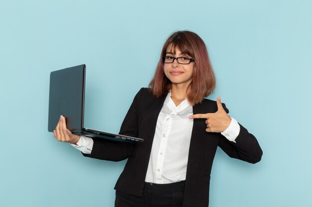 Weibliche Büroangestellte der Vorderansicht, die ihren Laptop auf der blauen Oberfläche hält