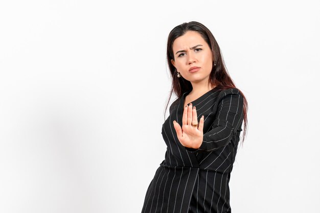 weibliche Büroangestellte im strengen schwarzen Anzug, der auf Weiß aufwirft