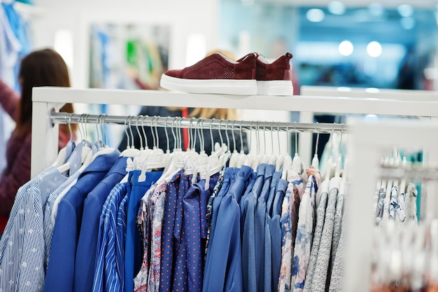 Weibliche bunte Kleidung auf den Regalen mit Schuhen in der brandneuen modernen Boutique des Bekleidungsgeschäfts