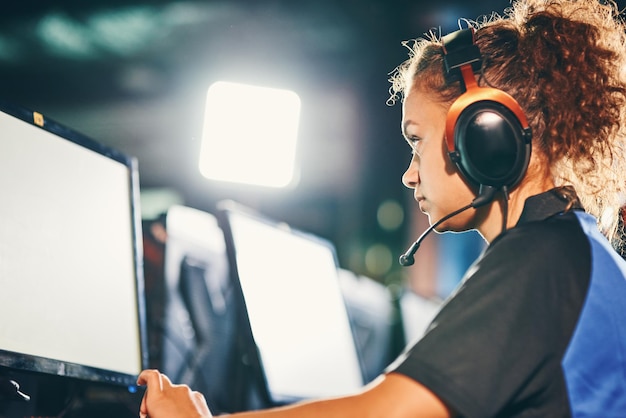Weibliche cybersport-gamer-seitenansicht eines jungen, voll konzentrierten mixed-race-mädchens mit kopfhörern