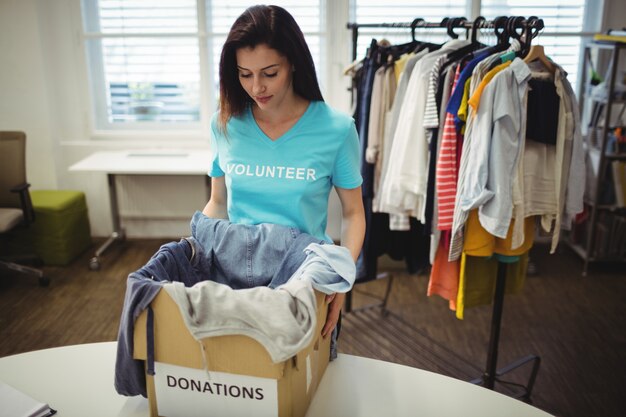 Weibliche Freiwillige halten Kleidung in Spendenbox