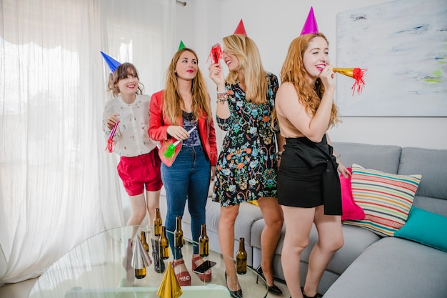 Weibliche Freunde mit Hörnern und Hüten auf Party