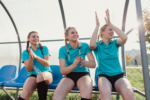 Kostenloses Foto weibliche fußballspieler, die auf einer bank sitzen und klatschen