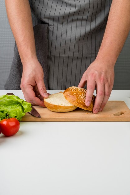 Weibliche Hände, die einen Burger zubereiten