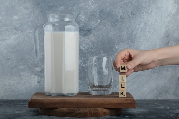 Weibliche Hände, die hölzerne Buchstaben mit frischer Milch halten.