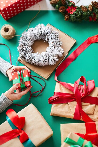 weibliche Hände, die Weihnachtsgeschenke und Kranz halten