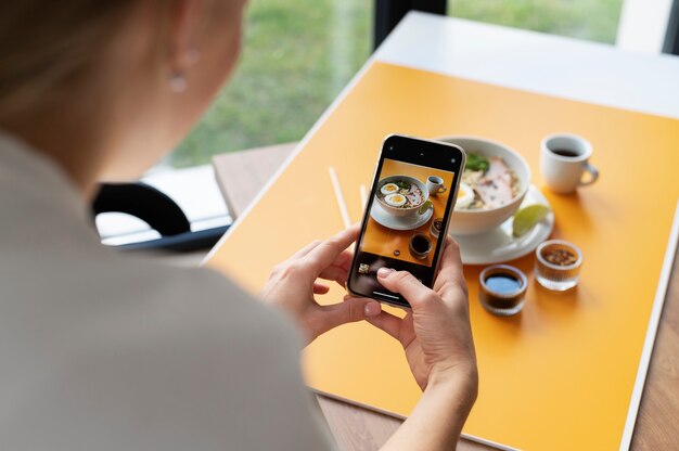 Weibliche Hände fotografieren eine Schüssel Ramen