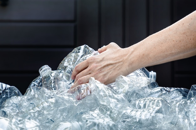 Weibliche Hände greifen nach Plastikflaschen, um sie zu sammeln und wegzuwerfen