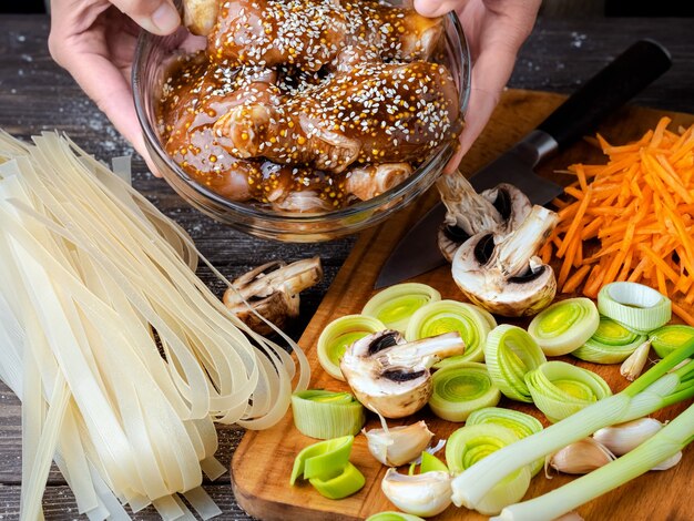 Weibliche Hände halten eine Schüssel Huhn mit Teriyaki-Sauce und Sesam