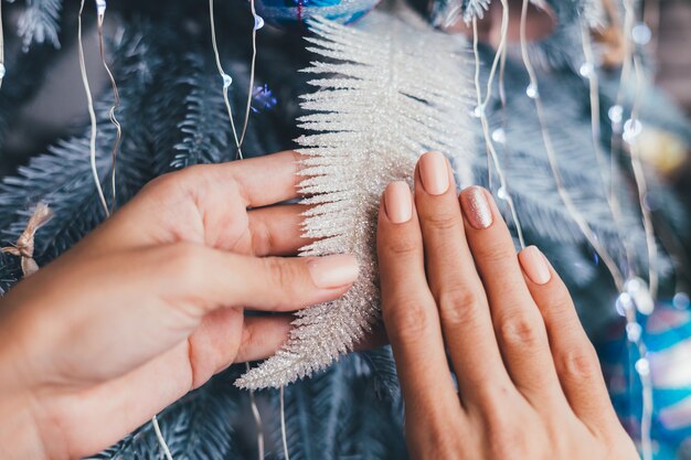 Weibliche Hände mit Weihnachten Neujahrsnageldesign. Nude beige Nagellack Maniküre, ein Finger glänzend goldene Bronze