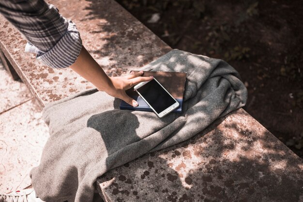 Weibliche Hand auf Mantel mit Buch und Telefon