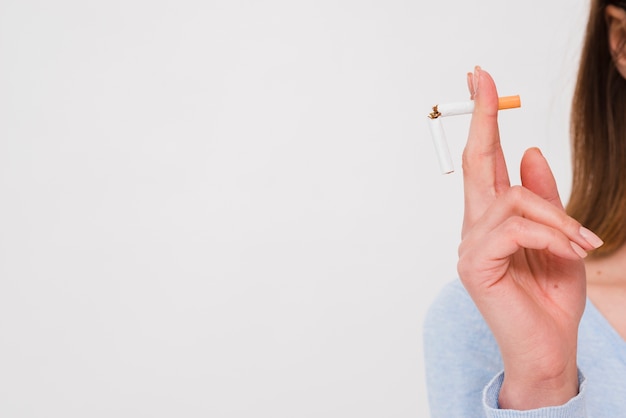 Weibliche hand, die gebrochene zigarette lokalisiert auf weißem hintergrund hält