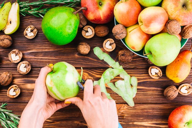 Weibliche Hand, die grünen Apfel mit Schäler abzieht