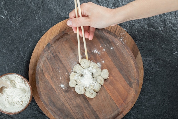 Weibliche Hand, die Knödel mit Stäbchen vom Teller nimmt.