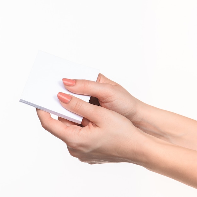Weibliche Hand, die leeres Papier für Aufzeichnungen auf Weiß hält.