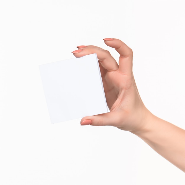 Weibliche Hand, die leeres Papier für Aufzeichnungen auf Weiß hält.