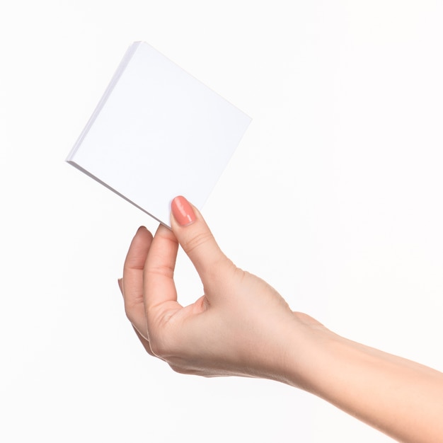 Weibliche Hand, die leeres Papier für Aufzeichnungen auf Weiß mit rechtem Schatten hält