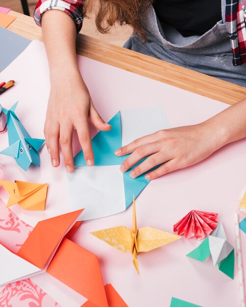 Weibliche Hand, die Papier bei der Herstellung des dekorativen Origamikunsthandwerks faltet