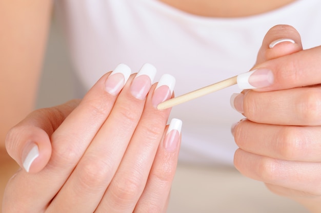 Weibliche Hand mit einem Kosmetikstift zum Reinigen der Nagelhaut