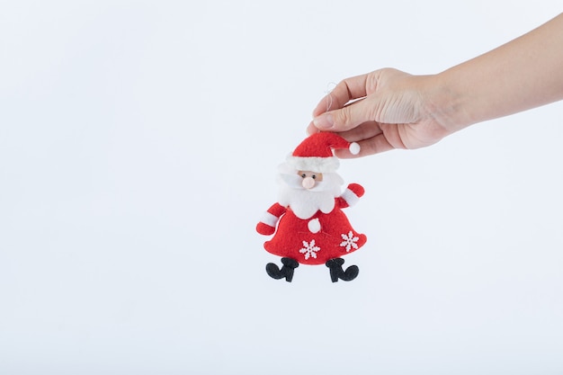 Weibliche Hand mit Weihnachtsmann-Figur auf weißer Oberfläche