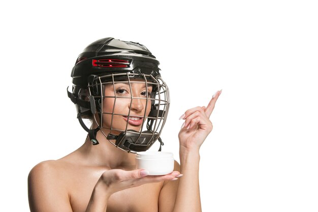 Weibliche Hockeyspielerin im Helm und in der Maske über weißer Studiowand