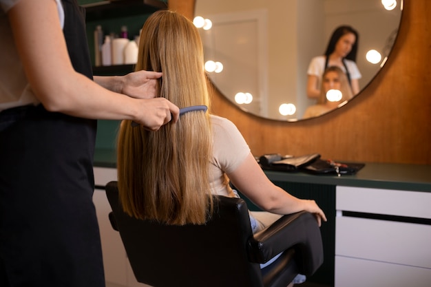 Weibliche Klientin beim Friseur, die sich die Haare macht