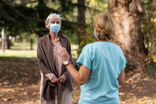 Weibliche Krankenschwester, die ältere Frau im Freien am Pflegeheim prüft