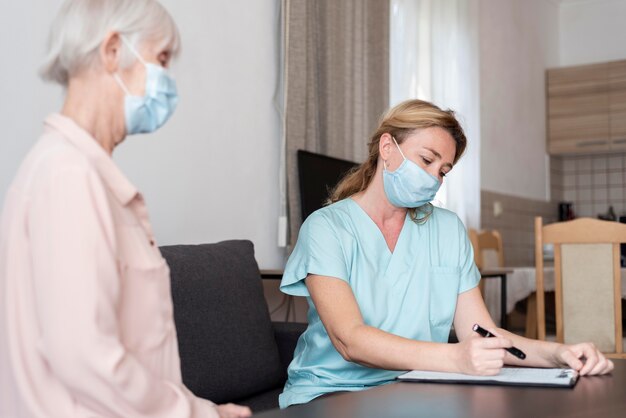 Weibliche Krankenschwester während einer Untersuchung mit älterer Frau im Pflegeheim