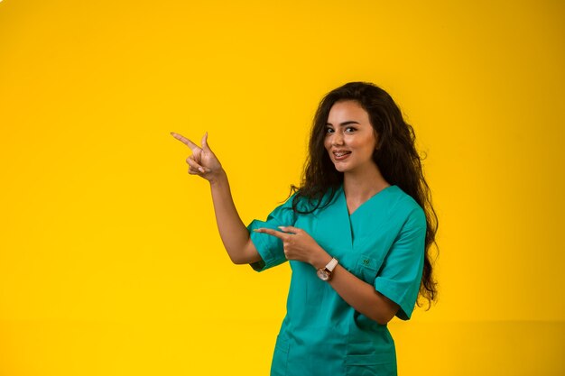 Weibliche Krankenschwester zeigt auf etwas mit der Hand.