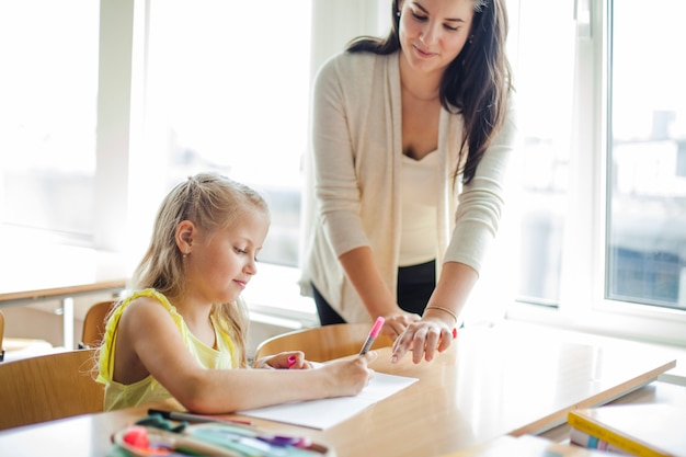 Weibliche Lehrerin hilft Schulmädchen