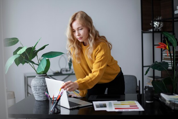 Weibliche Logo-Designerin, die an ihrem Tablet arbeitet, das mit einem Laptop verbunden ist