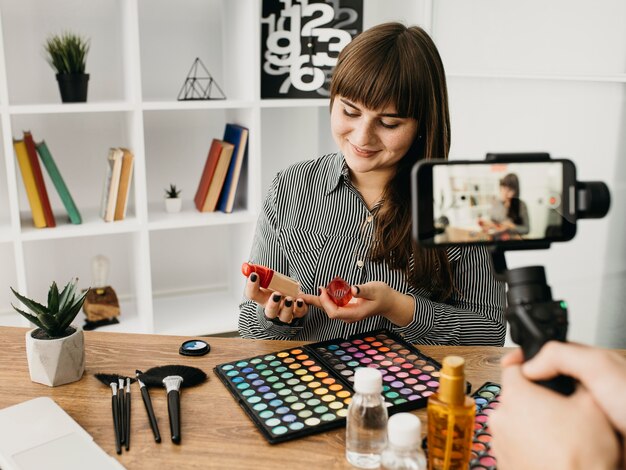 Weibliche Make-up-Bloggerin mit Streaming mit Smartphone zu Hause