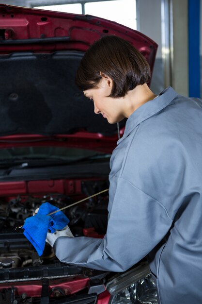 Weibliche Mechaniker den Ölstand in einem Automotor Überprüfung